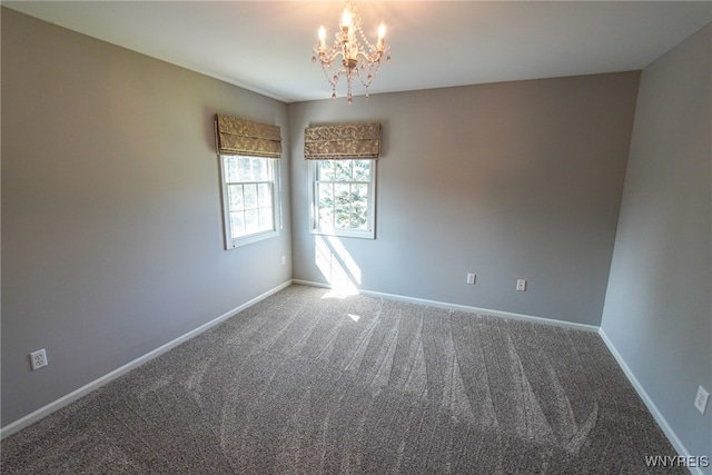 carpeted empty room with a notable chandelier