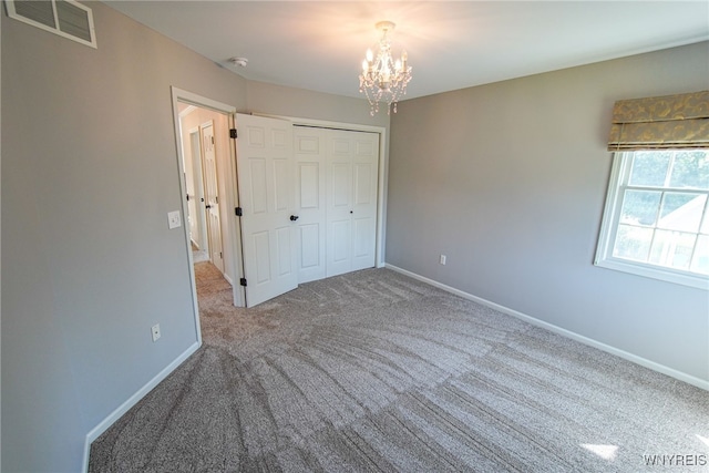 unfurnished bedroom featuring carpet flooring, an inviting chandelier, and a closet