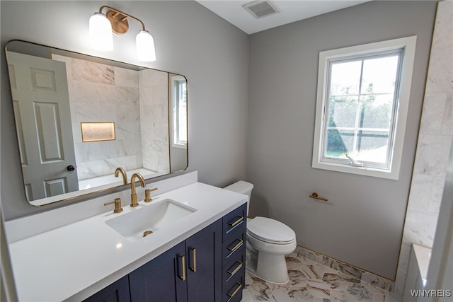 bathroom featuring plenty of natural light, vanity, toilet, and a bathtub