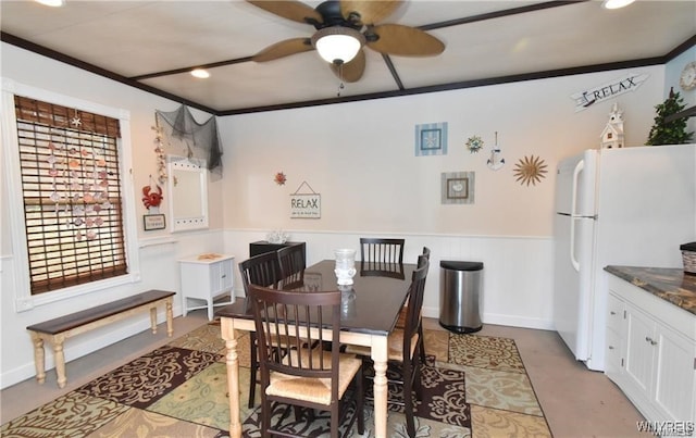 dining space with crown molding, ceiling fan, and wooden walls