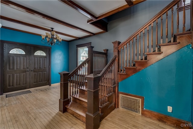 entryway featuring light hardwood / wood-style flooring, a notable chandelier, and beamed ceiling