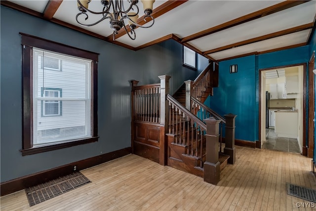 stairway with a wealth of natural light, an inviting chandelier, and hardwood / wood-style floors