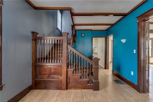 stairway with a wealth of natural light, wood-type flooring, and beam ceiling