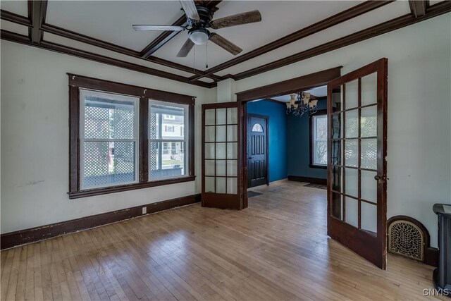 unfurnished room featuring light hardwood / wood-style flooring, ornamental molding, ceiling fan with notable chandelier, and french doors