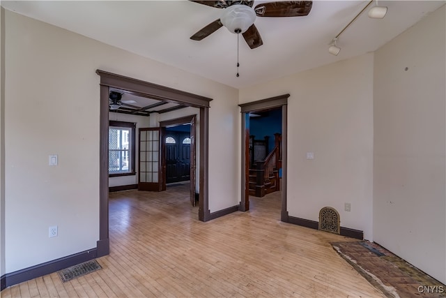 empty room featuring ceiling fan, light wood-type flooring, and track lighting