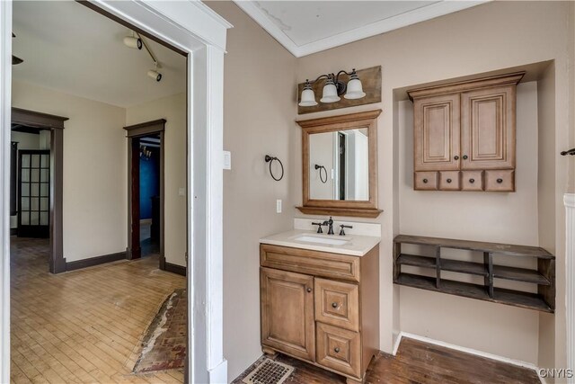 bathroom featuring crown molding, vanity, wood-type flooring, and track lighting