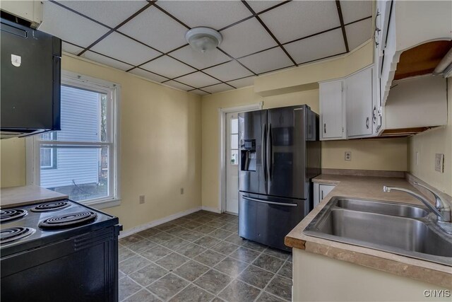 kitchen featuring a paneled ceiling, fridge with ice dispenser, sink, and white cabinets