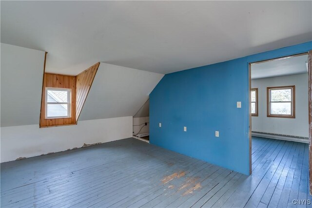 additional living space with lofted ceiling, a baseboard heating unit, and hardwood / wood-style floors