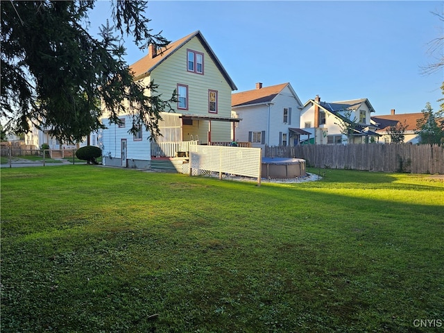 rear view of property featuring a yard and a covered pool