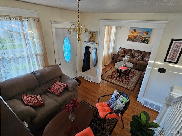 living room with a textured ceiling, wood-type flooring, and a chandelier