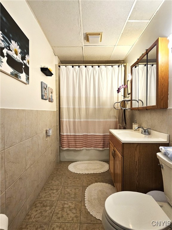 full bathroom with tile patterned floors, vanity, toilet, and tile walls