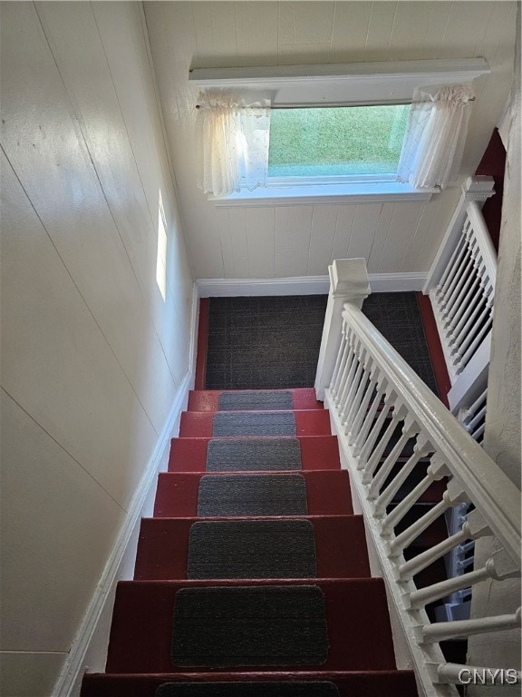 staircase with carpet floors and wooden walls