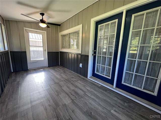 interior space featuring hardwood / wood-style floors, ceiling fan, and wood walls