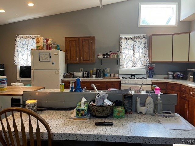 kitchen featuring white appliances and vaulted ceiling