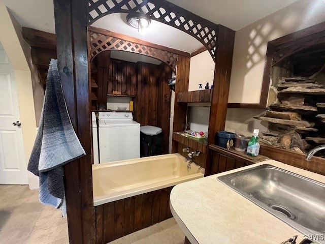 bathroom featuring a bath, washing machine and dryer, and sink