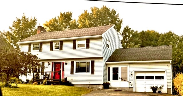 colonial-style house featuring a front yard and a garage