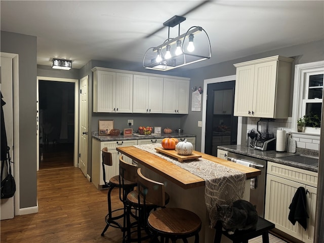 kitchen with white cabinetry, dark hardwood / wood-style flooring, a center island, stainless steel dishwasher, and wood counters