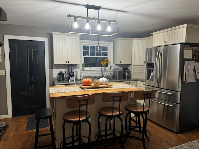 kitchen with backsplash, butcher block counters, dark hardwood / wood-style floors, and stainless steel fridge with ice dispenser