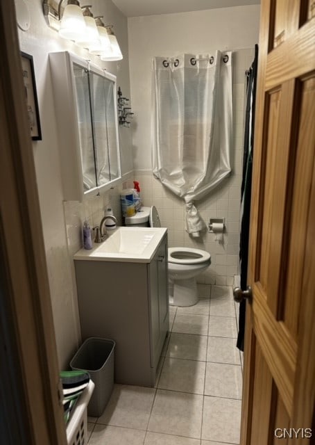 bathroom with vanity, toilet, tile walls, and tile patterned floors