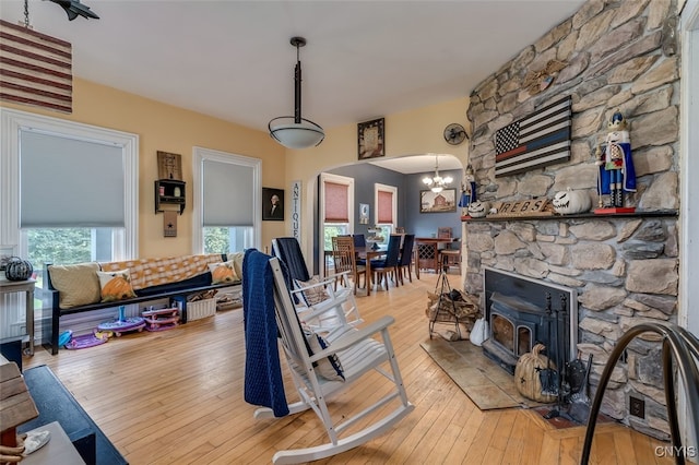 living room with a chandelier, a stone fireplace, and light hardwood / wood-style floors