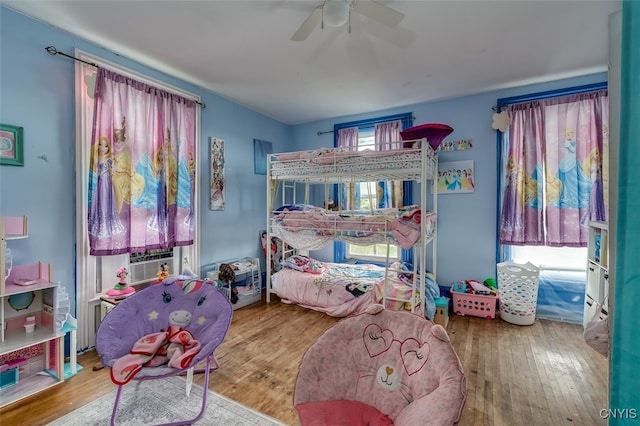 bedroom with cooling unit, hardwood / wood-style floors, and ceiling fan