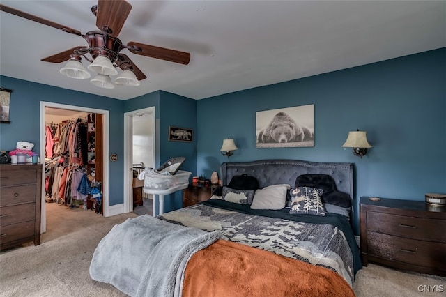 carpeted bedroom with ceiling fan, a closet, and a spacious closet