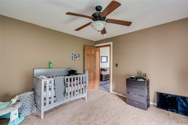 bedroom featuring light colored carpet, a crib, and ceiling fan