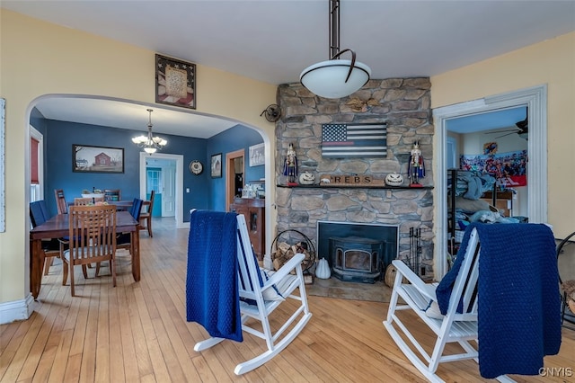 living room with ceiling fan with notable chandelier, hardwood / wood-style flooring, and a fireplace