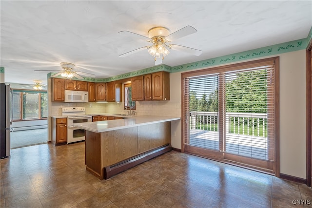 kitchen with white appliances, kitchen peninsula, sink, ceiling fan, and a baseboard heating unit