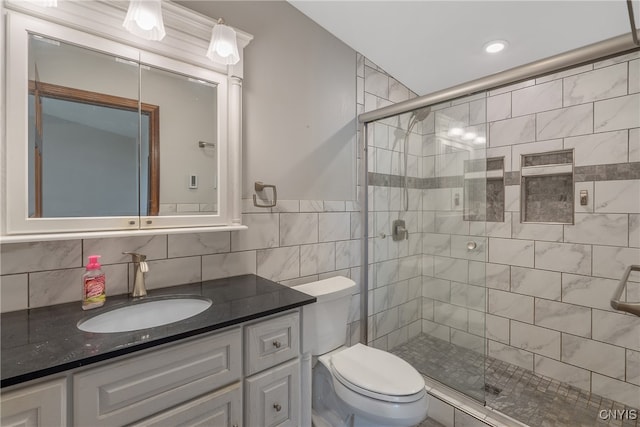 bathroom featuring a shower with door, vanity, tile walls, toilet, and decorative backsplash