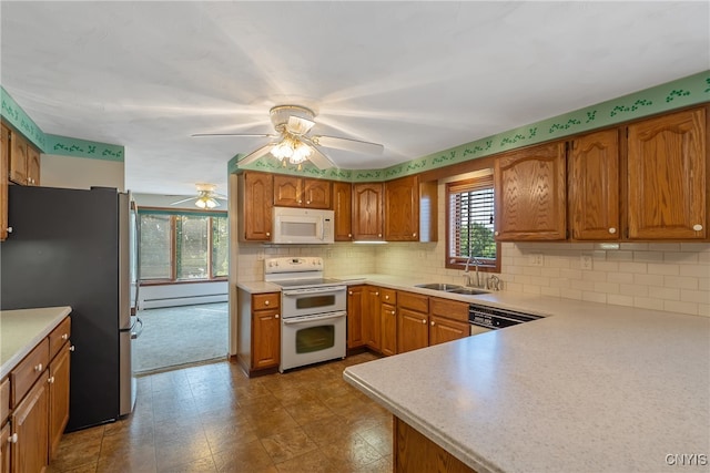 kitchen featuring appliances with stainless steel finishes, sink, decorative backsplash, a baseboard heating unit, and ceiling fan