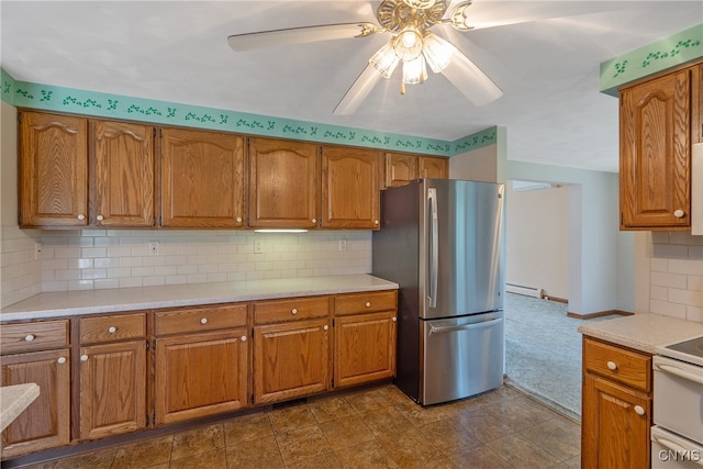 kitchen featuring baseboard heating, stainless steel fridge, white range, ceiling fan, and decorative backsplash