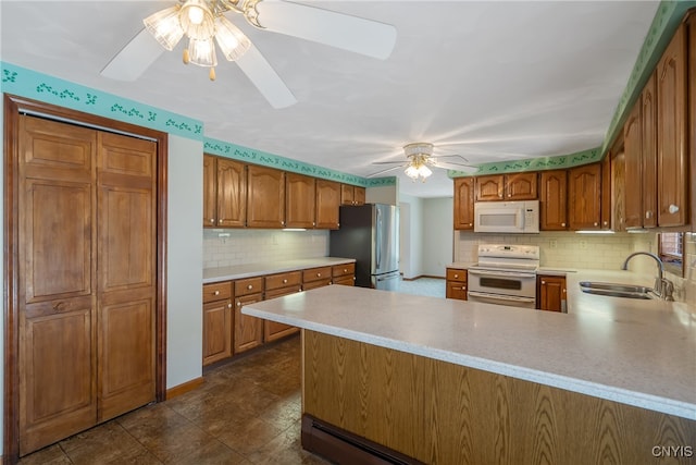 kitchen with white appliances, kitchen peninsula, sink, ceiling fan, and decorative backsplash