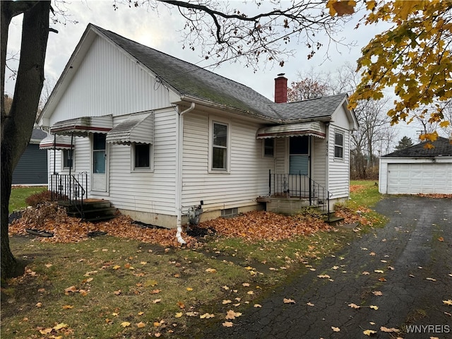 rear view of property featuring a garage and an outdoor structure