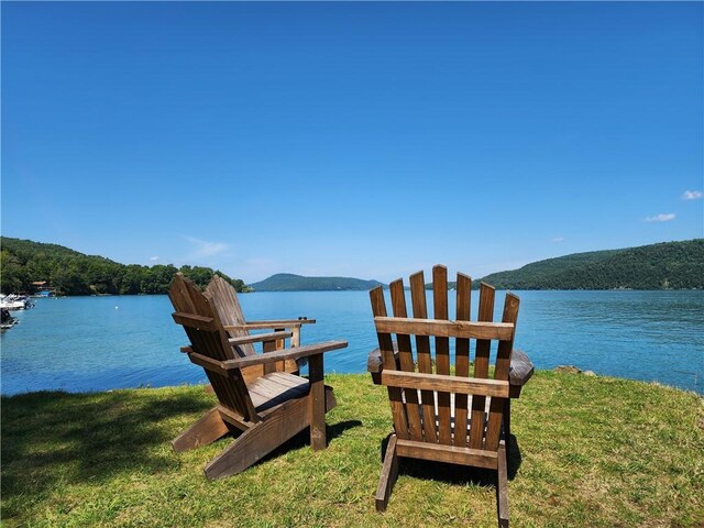 dock area with a yard and a water and mountain view