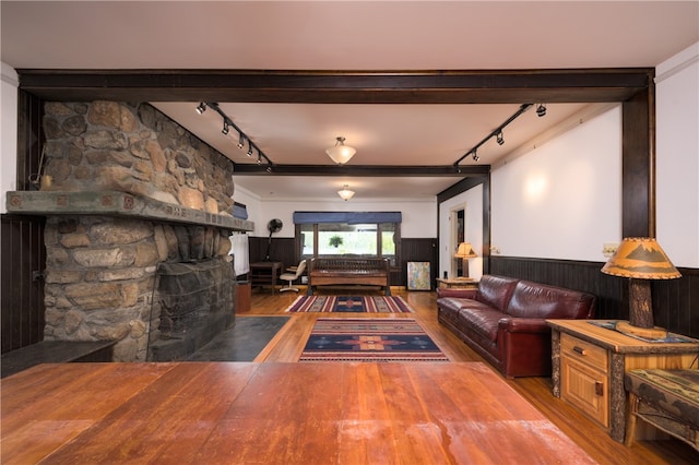 living room with rail lighting, hardwood / wood-style floors, and a stone fireplace