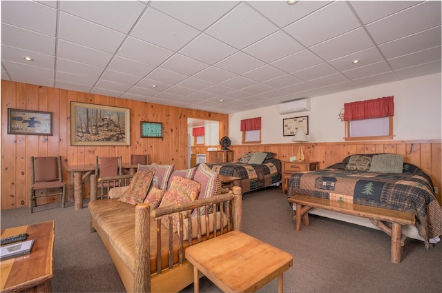 carpeted bedroom featuring a drop ceiling, a wall mounted AC, and wooden walls