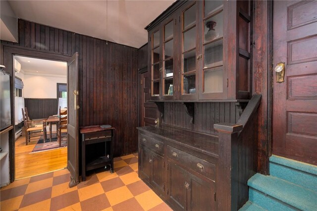 bar with dark brown cabinetry, light hardwood / wood-style flooring, and wood walls