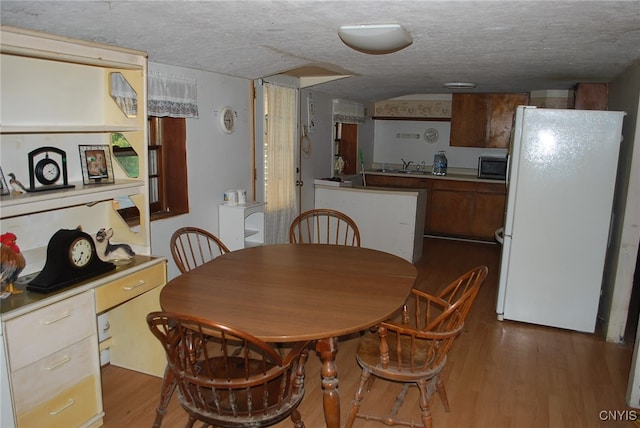 dining room with sink, dark hardwood / wood-style flooring, and a textured ceiling