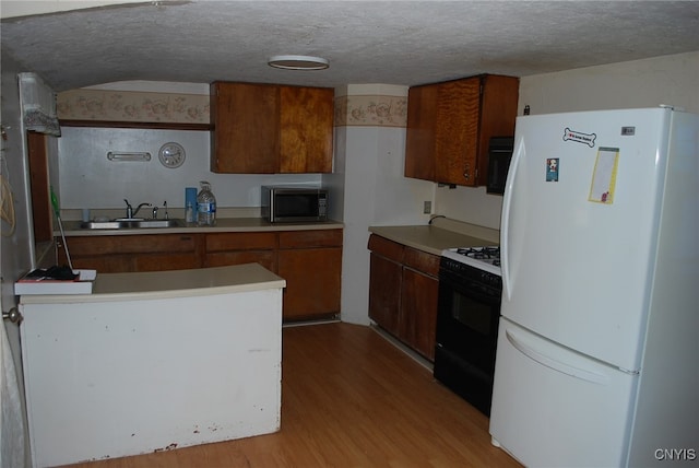 kitchen featuring a textured ceiling, black appliances, sink, and light hardwood / wood-style floors