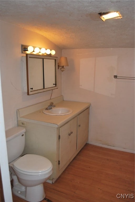 bathroom featuring a textured ceiling, vanity, vaulted ceiling, wood-type flooring, and toilet