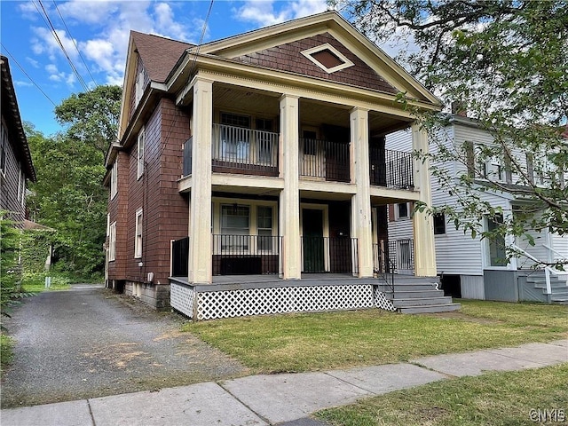 view of front of house featuring a front lawn and a balcony