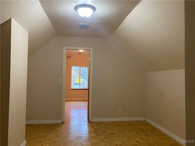 bonus room with light parquet floors and vaulted ceiling