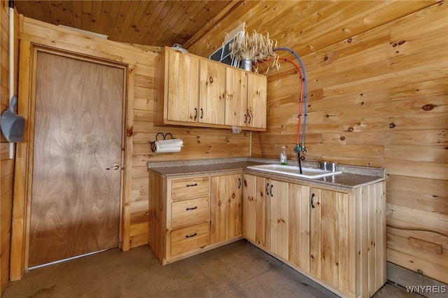 kitchen with wooden ceiling, light brown cabinetry, sink, and wooden walls