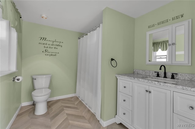 bathroom with vanity, toilet, and parquet flooring