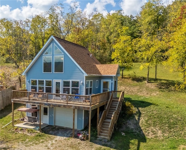 back of property with a garage, a wooden deck, and a yard