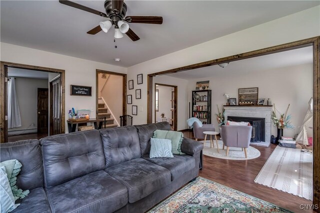 living room featuring a baseboard heating unit, ceiling fan, and wood-type flooring