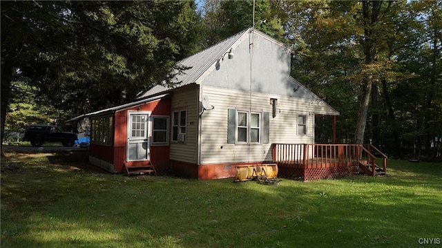 back of house featuring a lawn and a deck