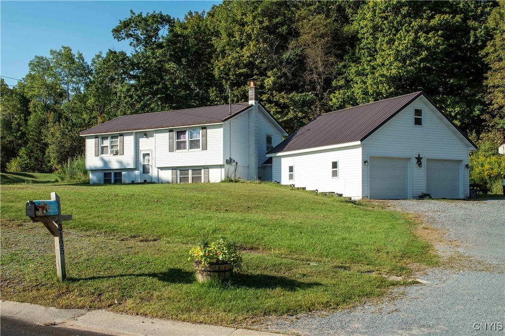 split foyer home with a garage, a front lawn, and an outbuilding