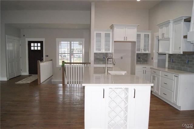 kitchen with white cabinetry, sink, an island with sink, dark wood-type flooring, and decorative backsplash